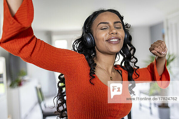 Happy woman dancing with headphones at home