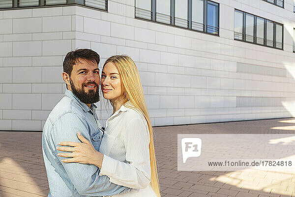Happy man with woman standing in front of building