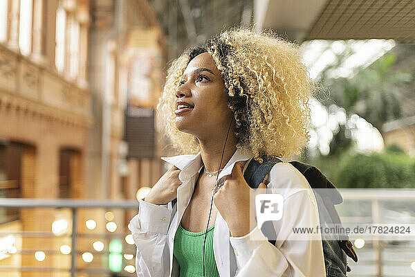 Excited woman carrying backpack looking up