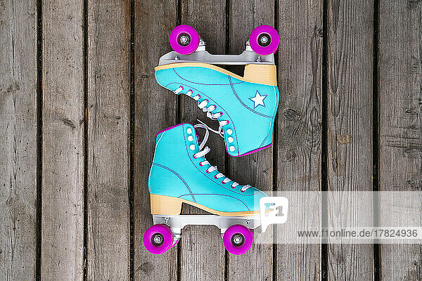 Multi colored roller skates on floorboard