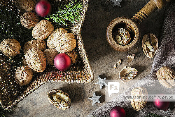 Studio shot of cutting board  star shaped wicker basket  Christmas ornaments  walnuts and simple nutcracker