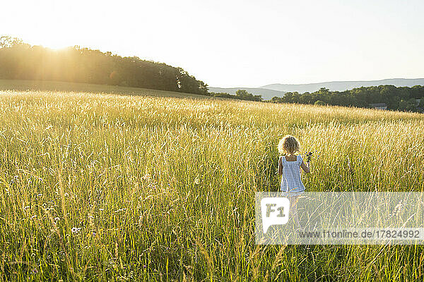 Mädchen läuft an einem sonnigen Tag auf dem Feld