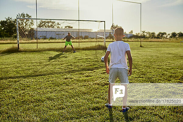Boy standing at sports field on sunny day