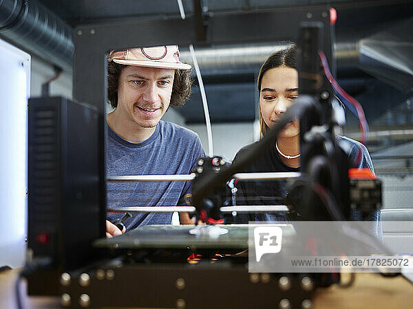 Engineer and colleague operating 3d printer working at workshop