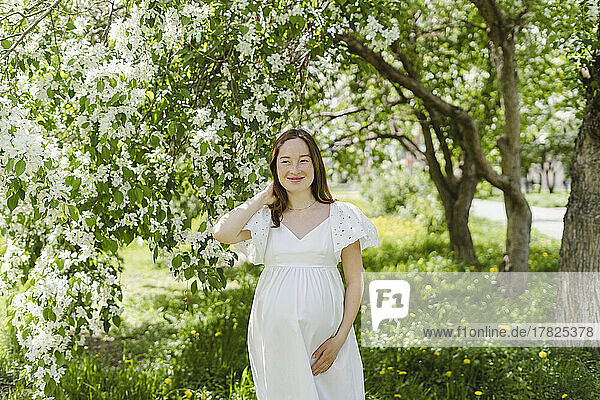 Smiling pregnant woman standing in park