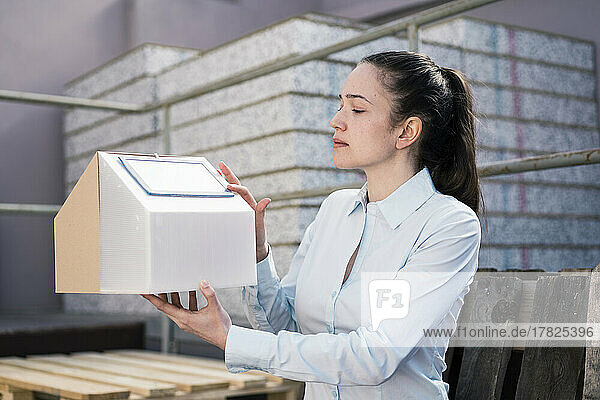 Businesswoman analyzing house model with solar panels in factory