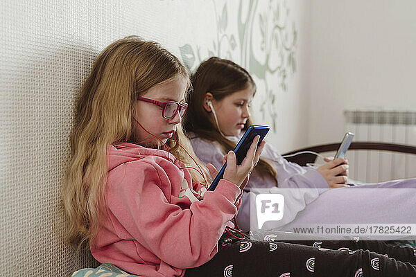 Siblings using mobile phones at home