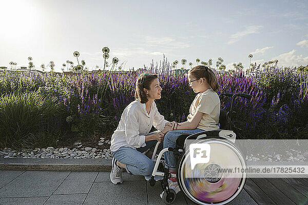 Woman talking to daughter with disability by flowers