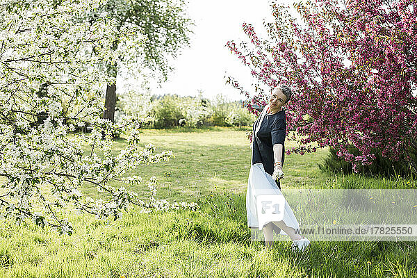 Glückliche Frau mit weißen Blumen  die im Garten tanzen