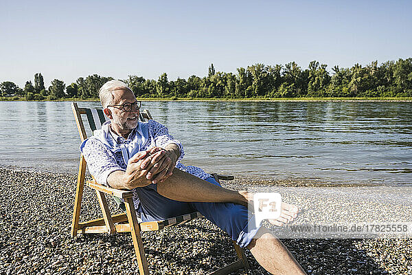 Lächelnder älterer Mann mit Brille am Flussufer
