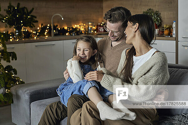 Smiling girl with parents enjoying in living room
