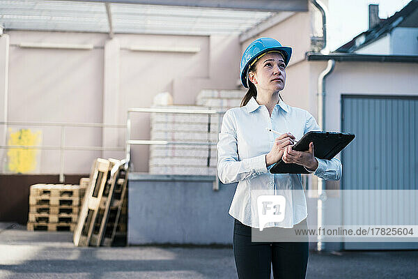 Young woman standing with tablet PC at factory