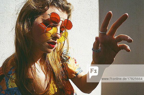 Woman wearing red and yellow sunglasses gesturing on sunny day