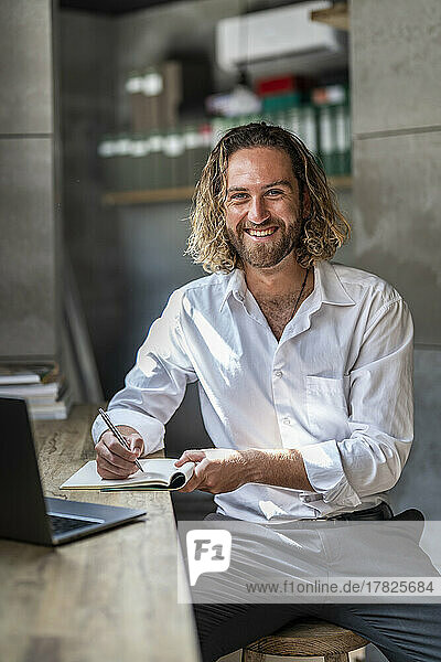Smiling businessman with pen and diary in office