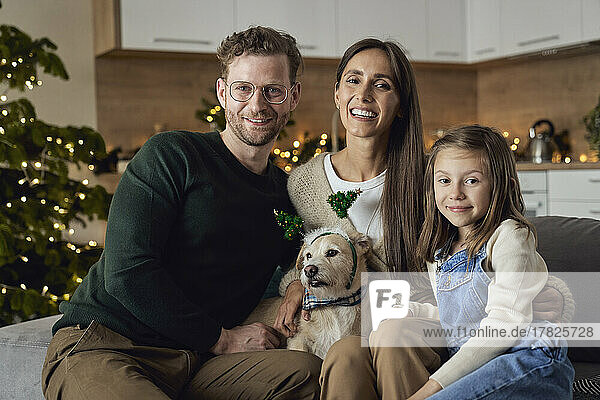 Smiling family with dog sitting on sofa in living room