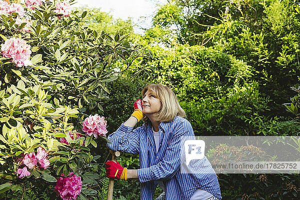 Nachdenkliche Frau stützt sich auf eine Schaufel vor Pflanzen im Garten