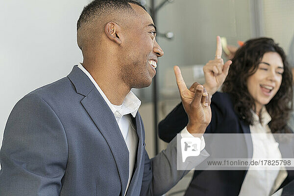 Happy businessman gesturing with colleague in office