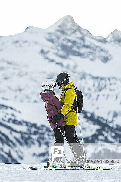 Romantic couple in ski wear embracing at Baqueira Beret resort  Pyrenees  Spain