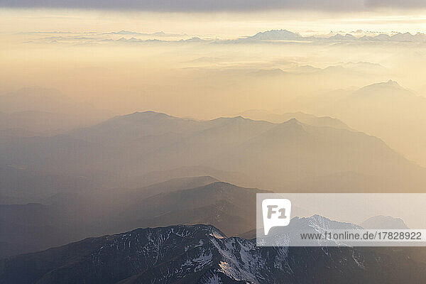 Luftaufnahme von Nebel bei Sonnenuntergang über den majestätischen Lepontinischen Alpen und dem Monte Rosa in den Wolken  Blick aus dem Flugzeug  Schweiz  Europa