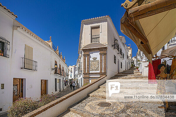 View of whitewashed houses and clothes shop on narrow street  Frigiliana  Malaga Province  Andalucia  Spain  Mediterranean  Europe