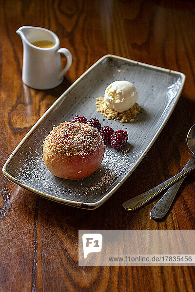 A baked apple with crumble  blackberries and ice cream