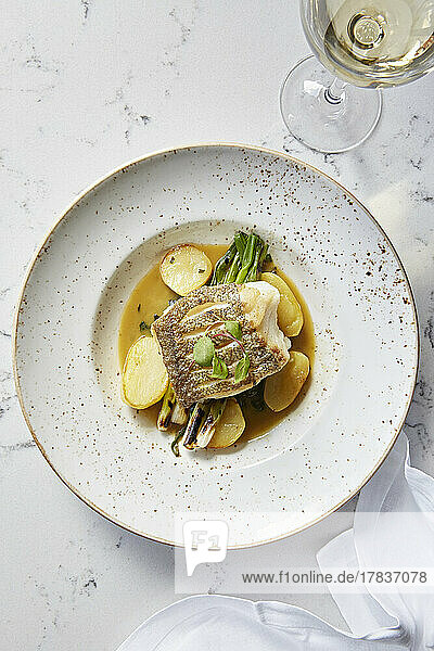 Pan seared fish with potatoes and asparagus served with white wine
