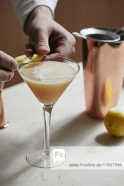 Whiskey-Sour-Cocktail mit Zitronenschale garnieren