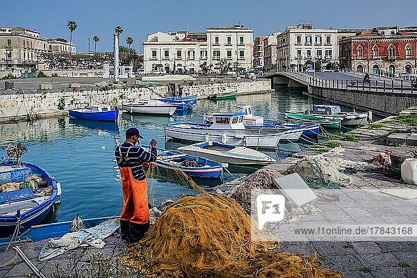 Fischer beim Netze flicken am Fischerhafen mit Booten vor der Altstadt  Syrakus  Ostküste  Sizilien  Italien  Europa
