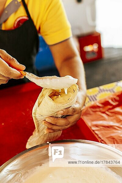 Hände bei der Herstellung eines nicaraguanischen Quesillo. Nahaufnahme der Hände bei der Herstellung eines traditionellen Quesillo mit eingelegten Zwiebeln. Zubereitung eines nicaraguanischen quesillo  traditionelles mittelamerikanisches Essen quesillo