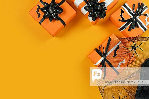 Traditional decorated gift boxes for Halloween with small bats and mesh with spiders on yellow background with empty copy space
