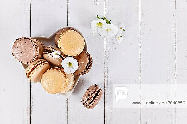 Natural brown  beige and cream colored French macarons on heart shaped plate with copy space