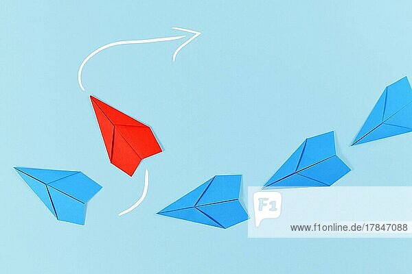 Rotes Papierflugzeug  das aus einer Reihe von blauen Flugzeugen herausfliegt. Konzept für neue Geschäftsstrategien  Führung  Entdeckung und anderes Denken