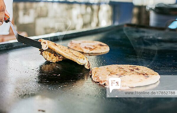 Spatula taking a traditional cheese pupusas on the grill  Close up of traditional artisan grilled pupusas. Traditional Nicaraguan pupusas with melted grilled cheese