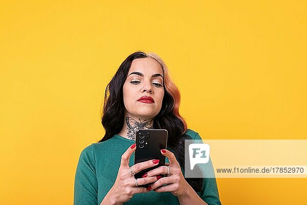 Porträt einer attraktiven Frau mit Smartphone auf gelbem Hintergrund. Kopierraum