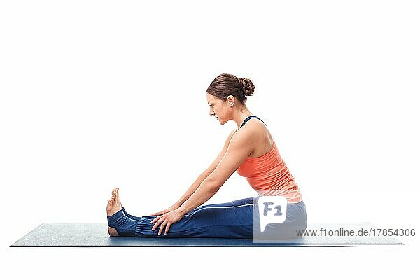Sportliche  fitte Frau bei der Ashtanga Vinyasa Yoga Rückenbeuge Asana Paschimottanasana  sitzende Vorwärtsbeuge Anfänger einfache Variante vor weißem Hintergrund