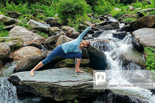 Sportlich fitte Frau übt Yoga-Asana Utthita Parsvakonasana  erweiterte Seitenwinkelhaltung im Freien am Wasser