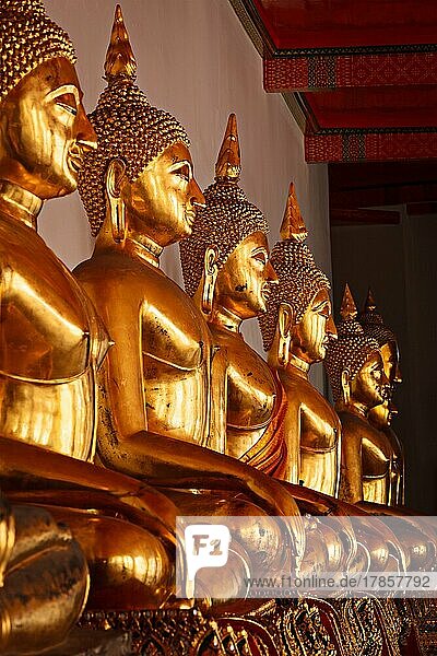 Reihe von vergoldeten sitzenden Buddha-Statuen im buddhistischen Tempel Wat Pho  Bangkok  Thailand. Niedriger Blickwinkel  Fokus auf den 3. von links