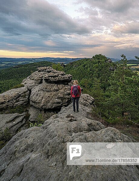 Frau in rot steht auf einem Felsen und beobachtet den Sonnenaufgang  Elbsandsteingebirge  Dresden  Deutschland  Europa