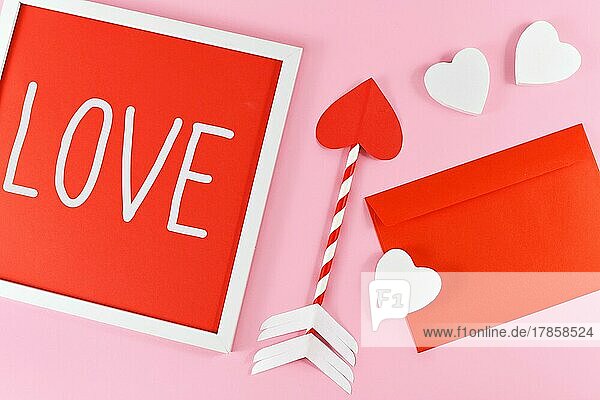 Valentinstag Zusammensetzung mit Bilderrahmen mit Text LIEBE  Amor Liebe Pfeile  roter Brief und weiße Herzen auf rosa Hintergrund