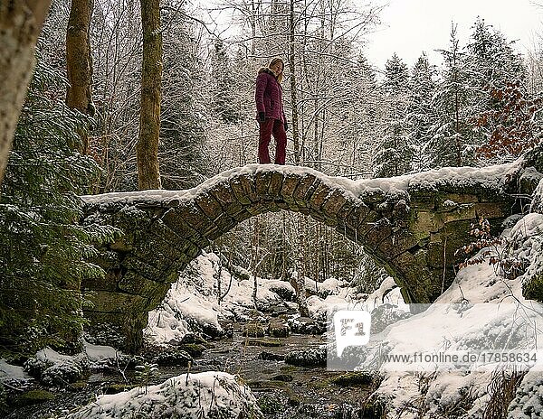 Frau in rot steht auf vereisten Brücke in Winterlandschaft  Schwarzwald  Deutschland  Europa