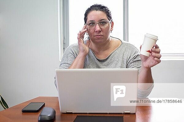 Porträt einer Frau  die an ihrem Laptop arbeitet und Kaffee trinkt