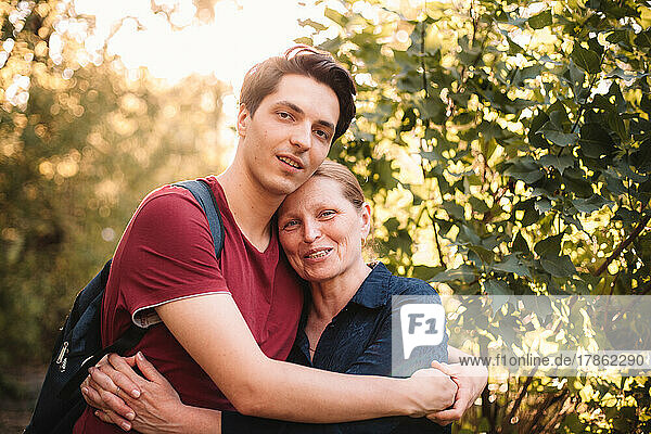 Portrait of happy mother and son embracing outdoors in summer