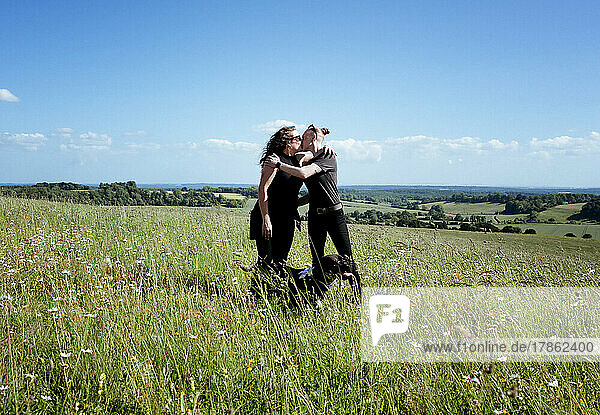 lesbian couple kissing in a field with their dog in the countryside
