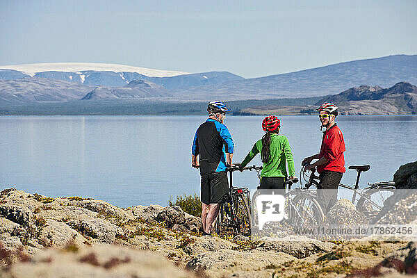 three friends cycling around Thinvallavatn lake in Iceland