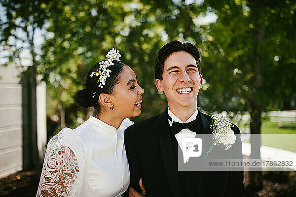 Latina bride and multiracial groom laugh and smile after wedding