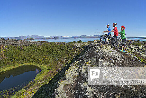 three friends exploring a volcanic crater on their mountain bikes