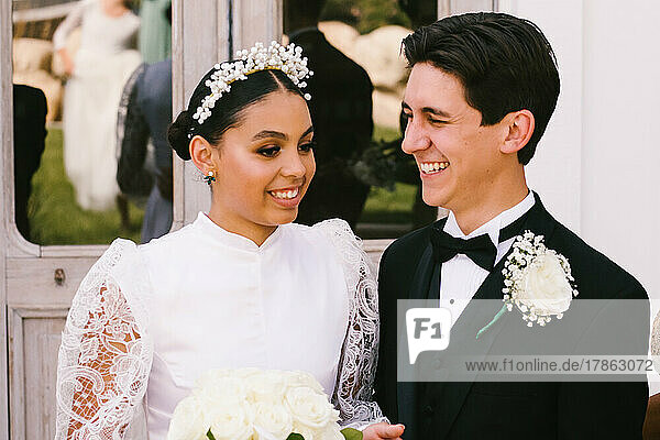 Latina bride and multiracial groom smile together after marriage