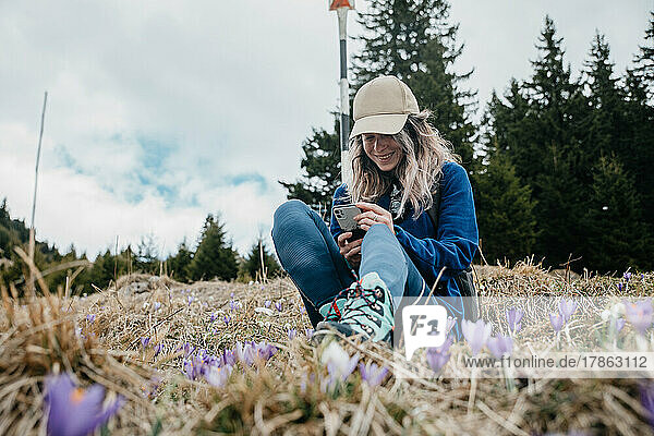 Mountain young girl looks at the phone and laughs in the nature