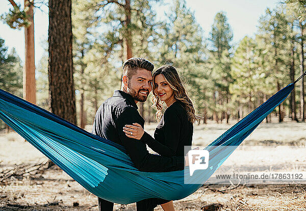 Couple sitting in hammock and smiles at the camera