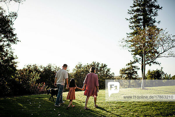 Family of Three Walking with Dog in Park in San Diego